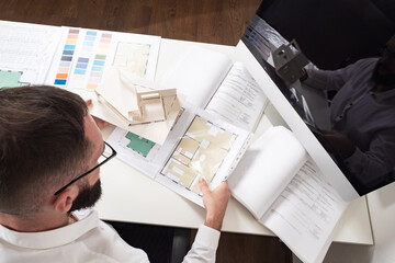 Poster - approval of the construction project. a man sits at a desk with a house plan, drawings, and color pa