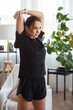 © Admiral - Attractive sports girl in black sportswear is doing a warm-up before practicing sports at home. Healthy lifestyle concept. Athletic woman stretches her arms before workout.
