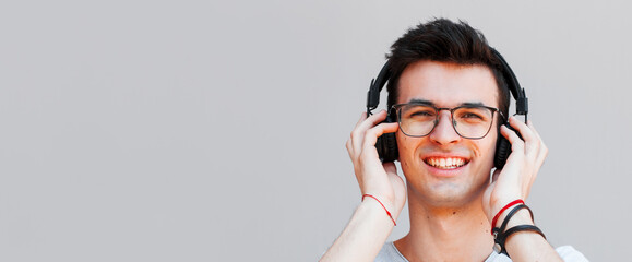 Wall Mural - Happy man smiling listening to music in headphones. Gray background.