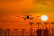 © Savvapanf Photo © - Silhouette of airplane during landing in front of amazing evening sky with sun, space for text