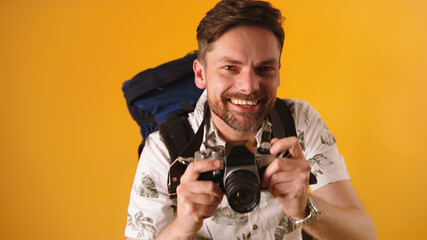 Wall Mural - Portrait shot of young caucasian bearded traveler smiling with backpack and camera. High quality photo