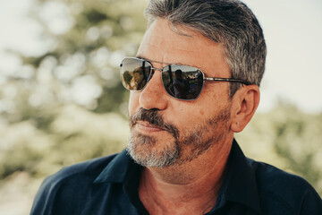 Adult man with sunglasses outdoors.