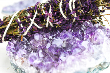 A close up image of a healing smudge stick with lilac flowers and amethyst crystal. 