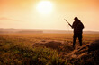 Hunter on the background of the sunset are on the field. Hunter In Sunrise With Shotgun in Autumn Season.