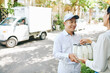 © DragonImages - Smiling milkman deliverying milk bottles to pretty female customer