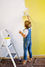 Funny Little Toddler Girl Painting The Wall With Color In New House. Family Repair Apartment Home. Happy Baby Child Paints The Wall, Choosing Color With Palette, Having Fun With Brush, Indoors