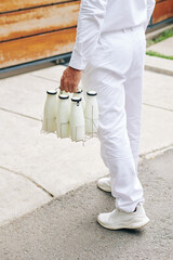 Wall Mural - Delvery man carrying glass bottles to entrance of customer