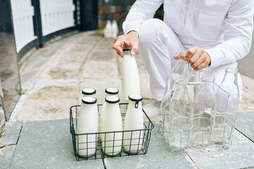 Wall Mural - Milkman putting glass milk bottles in wire crane and taking back empty bottles