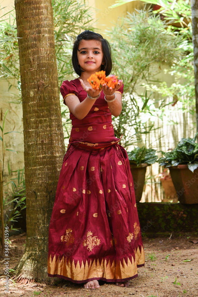 Photo Stock Kerala Onam festival, happy young Indian girl child, wearing traditional dress putting flower bed or Pookalam decoration floral pattern on Onam, Vishu, Diwali celebration, India. Indian festival. | Adobe Stock Photo Stock Kerala Onam festival, happy young Indian girl child, wearing traditional dress putting flower bed or Pookalam decoration floral pattern on Onam, Vishu, Diwali celebration, India. Indian festival. | Adobe Stock