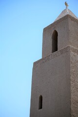 low angle view on old stone minaret by blue sky