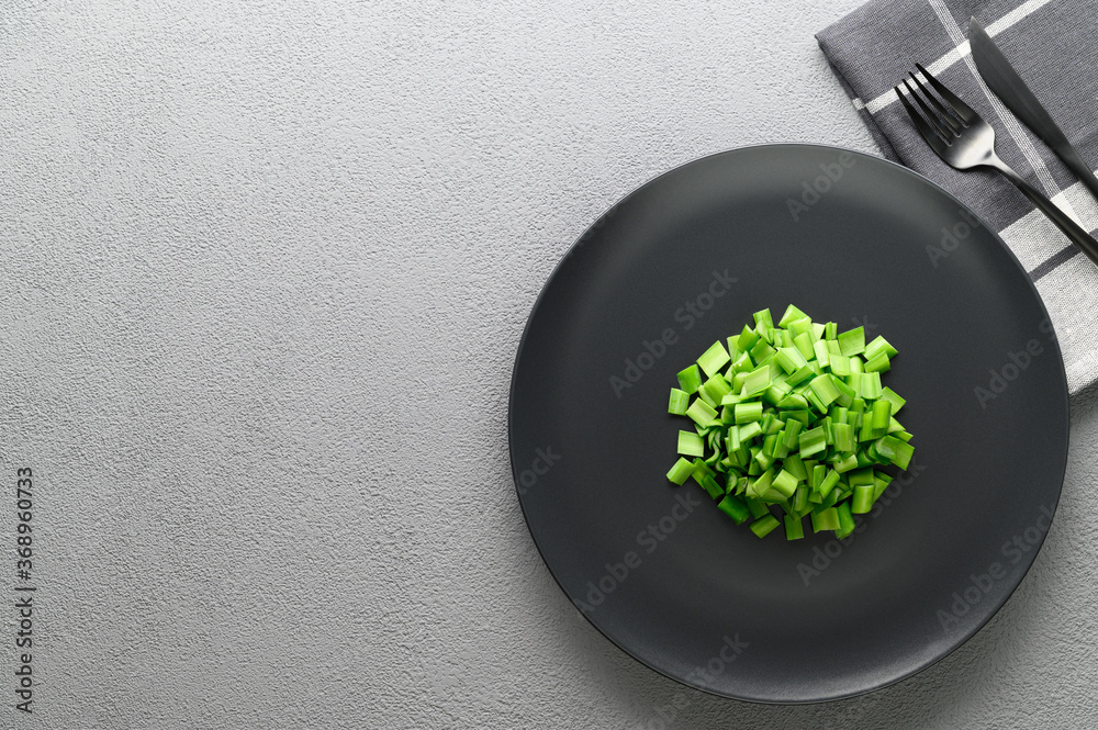 Sliced green onions in a black plate with a knife and fork. Allium ...