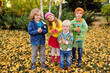 © Evgeniy Kalinovskiy - a group of preschoolers children play in the Park against the background of yellow autumn trees and throw up fallen leaves.