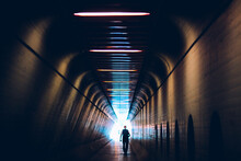 Silhouette Man Walking In Illuminated Tunnel