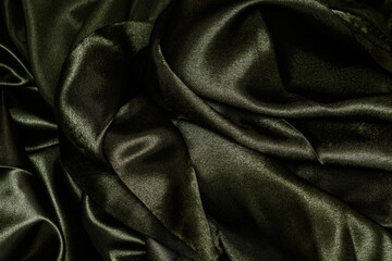Shiny dark green fabric. Dark green wavy fabric background.