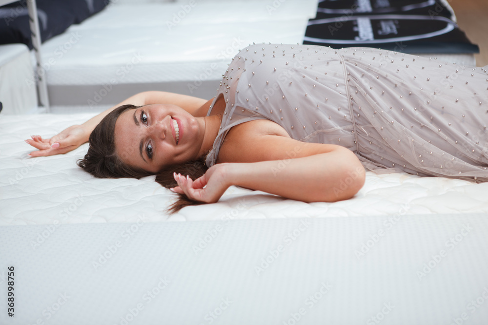 Happy curvy woman enjoying lying on orthopedic bed at furniture store, copy space - obrazy, fototapety, plakaty 