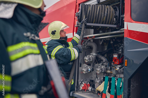 Fotografía Fireman wearing safe helmet standing next to the fire engine