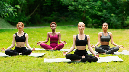 Wall Mural - Outdoor yoga class. Group of diverse girls doing breathing exercises or meditation in nature