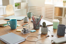 Background Image Of Cluttered Workplace Table With Cups, Mugs And Stationary Items, Teamworking Or Studying Concept, Copy Space