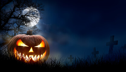 Wall Mural - a spooky halloween pumpkin, jack o lantern, with an evil face and eyes on the grass in a graveyard w