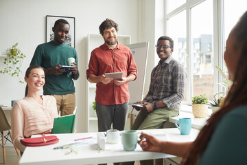 Wall Mural - portrait of cheerful multi-ethnic team talking to boss or manager during business meeting in office,