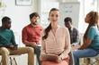 © Seventyfour - Multi-ethnic group of people sitting in circle while discussing business project in office, focus on elegant businesswoman ooking at camera in foreground, copy space