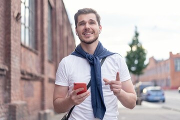 Canvas Print - Handsome smiling man listening to music while walking in the city.