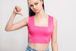 © golubovy - Dislike sign. Disapproval gesture. Disappointed skeptic woman in pink with dyed braids hairstyle showing thumb down isolated on white. Bad idea. Wrong choice. Disagreement signal. Loser shame.