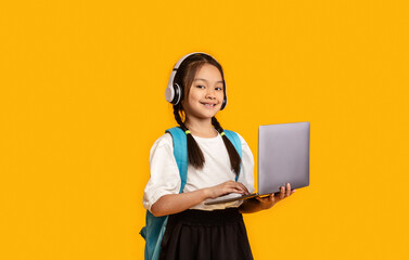 Asian School Girl With Laptop And Headphones Studying, Yellow Background