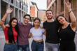 Portrait of a group of friends embraced in the city with hands in the air - Millennials smiling looking the camera - Concept of multiracial team of student in summer time that having fun together