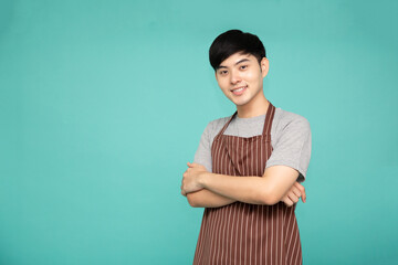 Portrait of Asian workers fresh market with brown apron standing with arms crossed isolated on green background