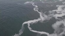 Slow Aerial Tilt From Seafoam To Horizon On Misty, Grey Indian Ocean