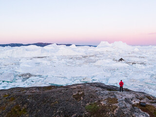 Wall Mural - travel in arctic landscape nature with icebergs - greenland tourist explorer. person looking at amaz