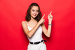 © dianagrytsku - Young woman showing pointing on red background. Very fresh and energetic beautiful young girl smiling happy presenting on red background.
