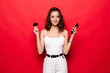 © dianagrytsku - Smile happily woman holding smartphone and credit card shopping online on red background.