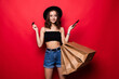 © dianagrytsku - Beautiful woman carrying shopping bags isolated on red background