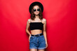 © dianagrytsku - Portrait of woman wearing in floppy hat and sunglasses isolated over red background