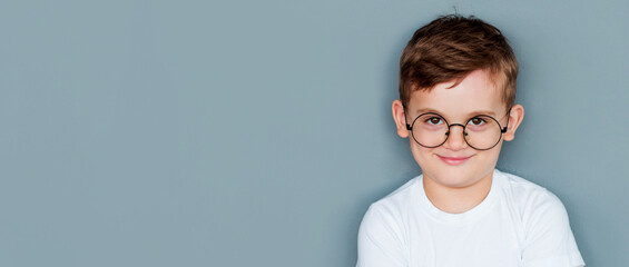 Wall Mural - Photo of adorable young happy boy wearing white t-shirt looking at camera over grey background