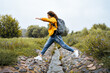 © Ivan Ozerov/Stocksy - Young girl traveler jumps over a stream