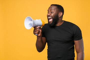 cheerful african american man in casual black t-shirt isolated on yellow background studio portrait.