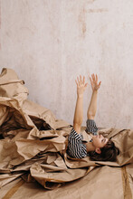 Creative Carefree Woman Emerging From Pile Of Craft Paper