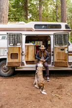 A Man Teaching His Dog Tricks Outside Of A Camper Van