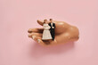© Natalie JEFFCOTT/Stocksy - vintage wedding cake figurines held in a hand on a pink background