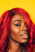 Closeup Portrait Of Happy Black Woman Posing Over Yellow Background With Red Wig