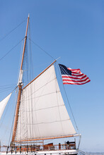 American Flag Waves In The Sky While Hanging From The Mast Of A Sail Boat.