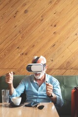 Senior man using vr glasses at restaurant