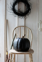 Black Pumpkin On Old Chair With Wreath