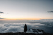 © Vladimir Tsarkov/Stocksy - anonymous female tourist stands on the edge of cliff above the clouds at dawn