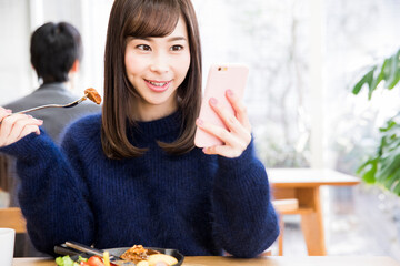 Wall Mural - 食事しながらスマホをする女性客