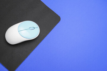 Modern computer mouse with mat on color background