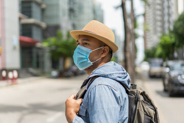 Young asian backpacker traveling in urban city wearing face mask for protect virus safety travel.